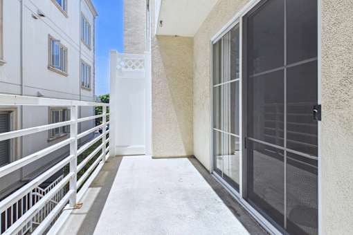 A balcony with a white railing and a glass door.