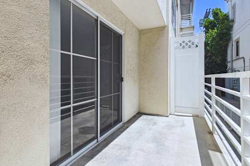 A balcony with a white railing and a sliding door.