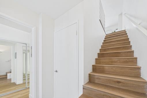 A wooden staircase with a white door on the side.