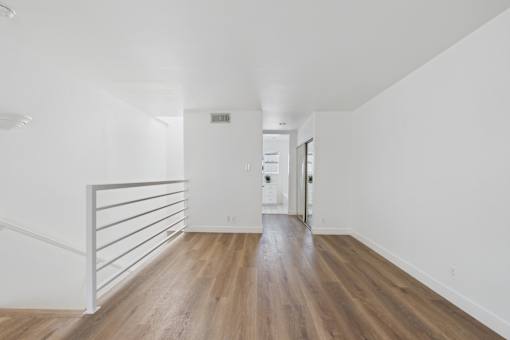 A long hallway with wood floors and white walls.