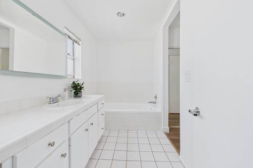 A white bathroom with a white tub and a white sink.