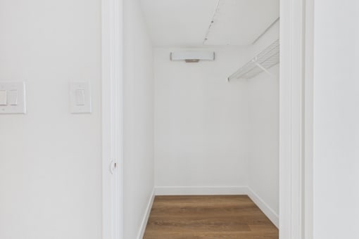 A white room with a light on the ceiling and a door on the left.