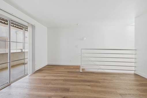 A room with a white bed frame and wooden flooring.