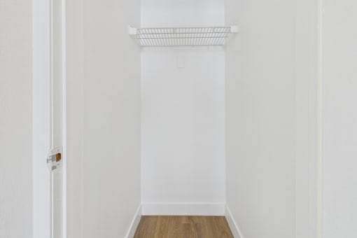 A white door with a white wall and a white shelf above it.