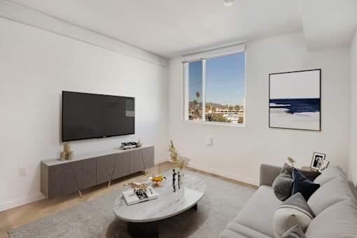 A living room with a grey couch, a white coffee table, and a flat screen TV.