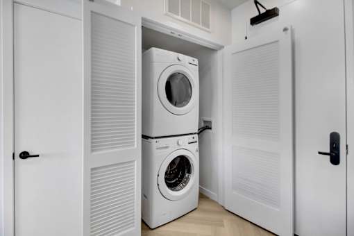 A white laundry room with a washer and dryer stacked on top of each other.