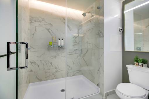 A white toilet sits next to a walk-in shower with a glass door.