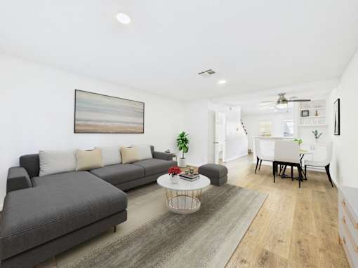 A living room with a grey sofa, a white coffee table, and a painting on the wall.