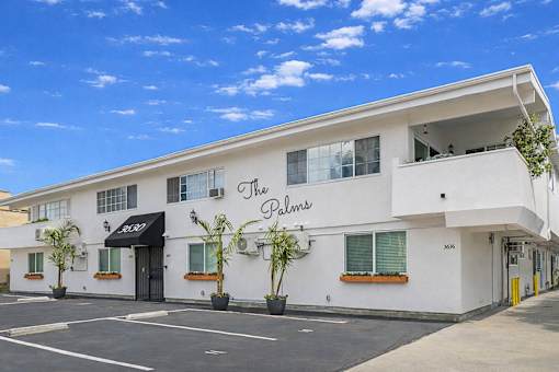 The Palms building has a black awning and a yellow door.