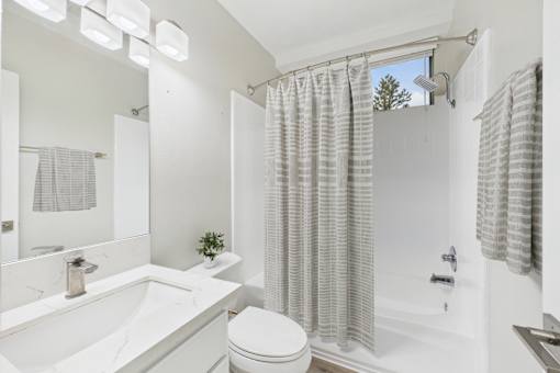 A white bathroom with a toilet, sink, and shower.