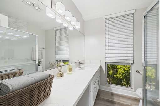 A bathroom with a white countertop and a window with blinds.