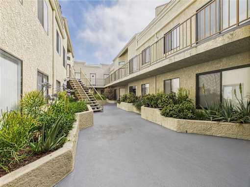 A long, narrow courtyard between two buildings with a staircase in the middle.