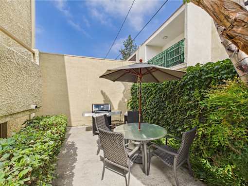 A patio with a table and chairs under an umbrella.