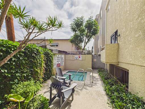 A small pool surrounded by a concrete patio and a black metal railing.