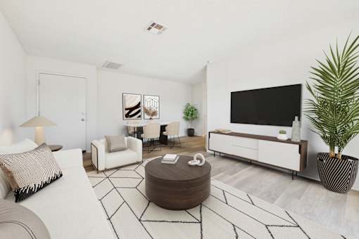 A living room with a white couch, a brown ottoman, and a black and white rug.