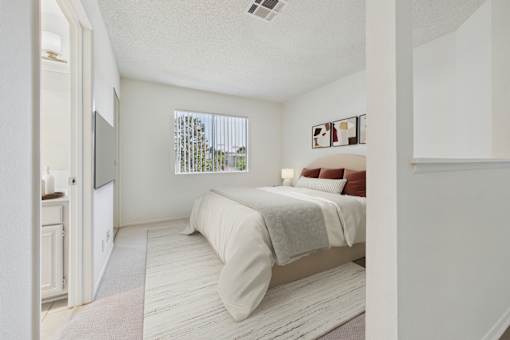 A bedroom with a bed, nightstand, and window.