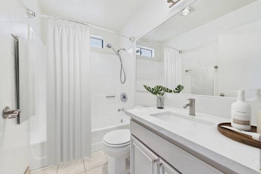 A white bathroom with a toilet, sink, and shower.