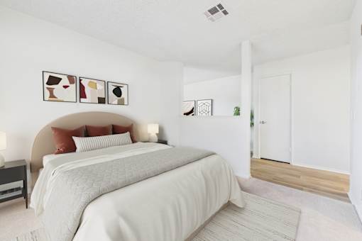 A bedroom with a large bed and a white wall.