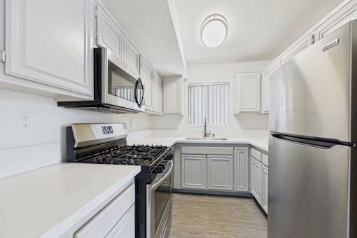 A modern kitchen with white cabinets and stainless steel appliances.