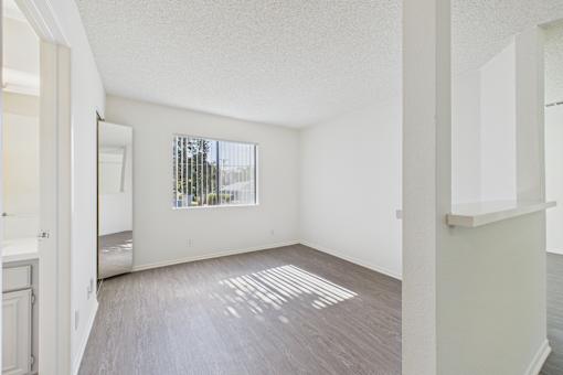 A room with a window and a wooden floor.