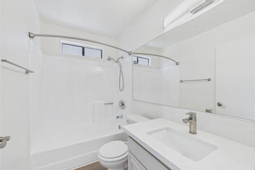 A white bathroom with a toilet, sink, and shower.