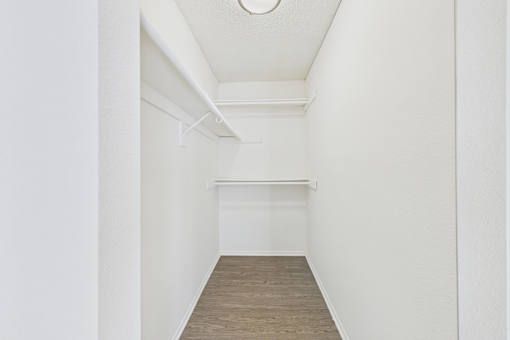 A long, narrow room with a white ceiling and a wooden floor.