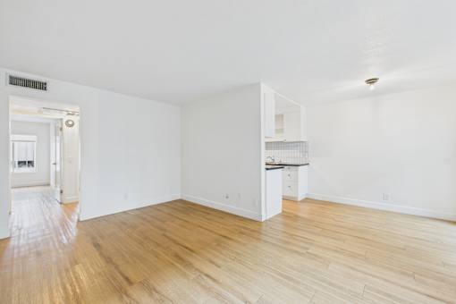 A room with wooden flooring and white walls.