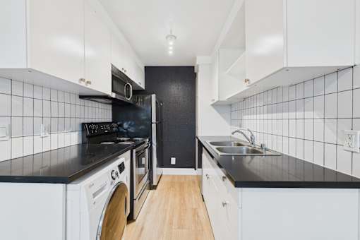 A black and white kitchen with a washing machine and a microwave.