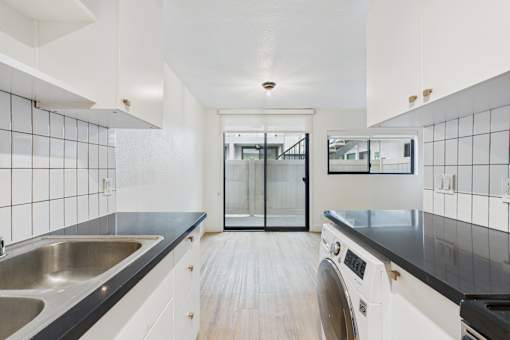 A modern kitchen with a black countertop and white cabinets.