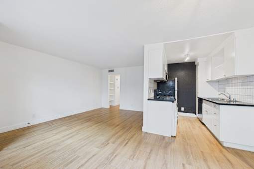 A kitchen with white cabinets and a black refrigerator.