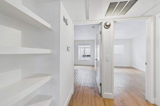 A hallway with white walls and wooden floors.