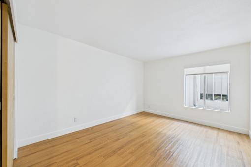 A room with wooden floors and a window with blinds.