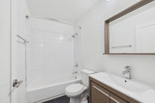 A white toilet sits next to a white sink in a small bathroom.