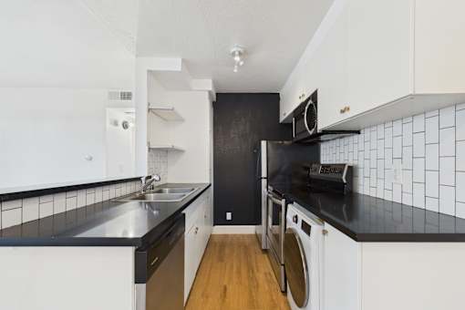 A modern kitchen with black countertops and white cabinets.