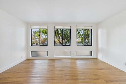 A room with wooden floors and three windows.