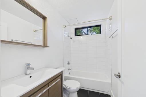 A white sink with a mirror above it and a white toilet next to a bathtub.