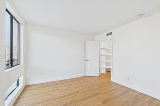 A white room with a wooden floor and a door on the right.