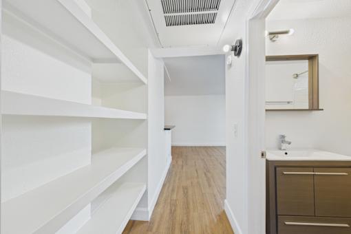 A white hallway with a mirror and a sink.