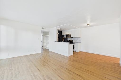 A kitchen area with white cabinets and a wooden floor.