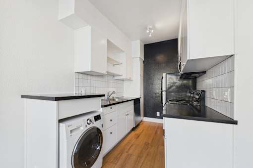 A modern kitchen with white cabinets and a black countertop.