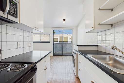 A kitchen with black countertops and white cabinets.