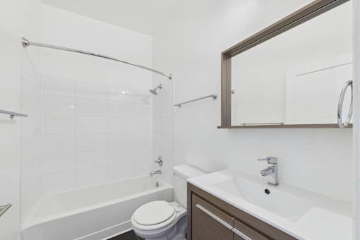 A white bathroom with a toilet, sink, and shower.