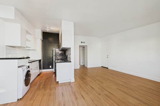 A kitchen with white cabinets and a wooden floor.