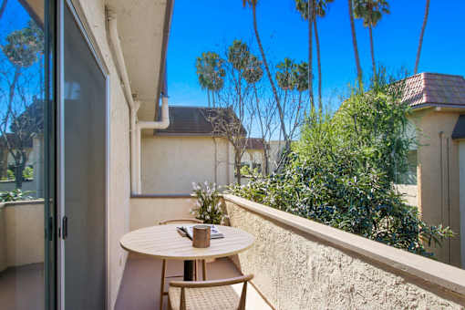 A patio with a table and chairs overlooking a garden.