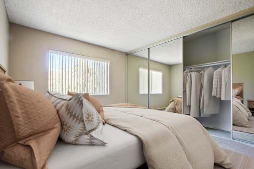 A bedroom with a bed, pillows, and a mirror.