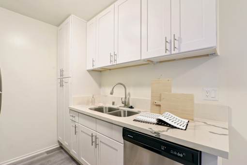 A kitchen with white cabinets and a black dishwasher.