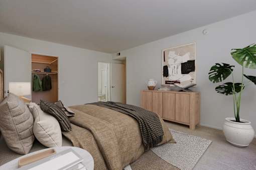 A bedroom with a bed, a nightstand, a wardrobe, and a plant.