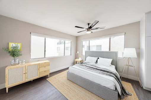 A bedroom with a bed, a ceiling fan, and a wooden cabinet.