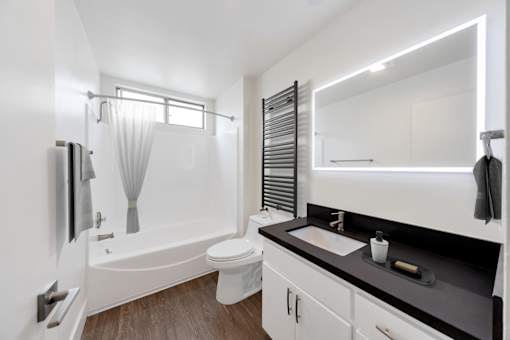 A white bathroom with a black counter top and a white toilet.