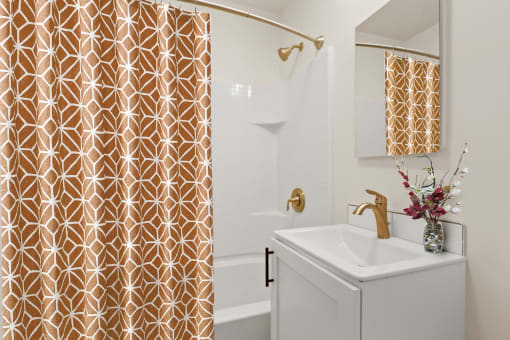 a bathroom with a white sink and gold shower curtain